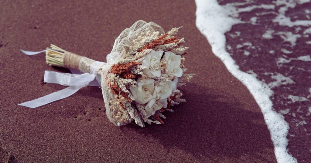 A wedding bouquet lies by the ocean, illustrating the idea of weddings in your dreams. 